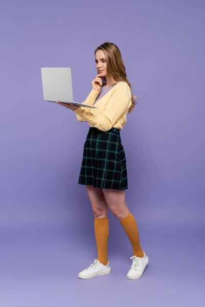 Full length of young woman using laptop on purple — Stock Photo