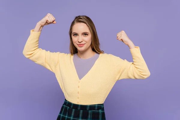 Happy young woman showing power gesture isolated on purple — Stock Photo