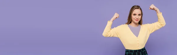 Happy young woman showing power gesture isolated on purple, banner — Stock Photo