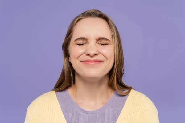 Pleased young woman with closed eyes isolated on purple — Stock Photo