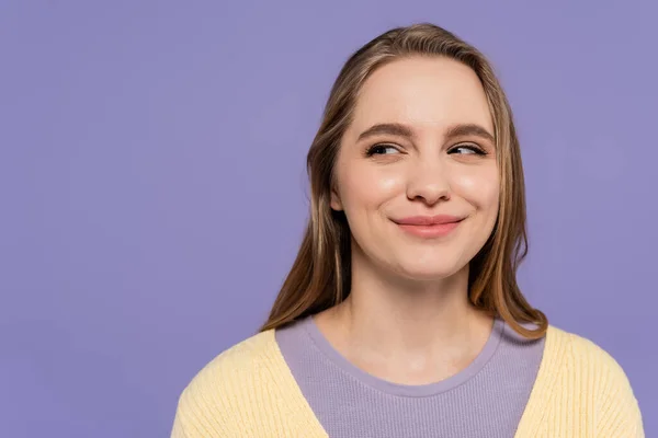 Astuta joven mujer mirando hacia otro lado y sonriendo aislado en púrpura - foto de stock