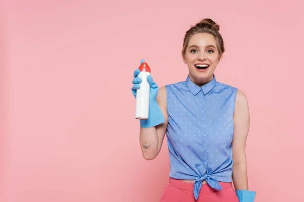 Aufgeregte junge Frau in Gummihandschuhen hält Lufterfrischungsflasche isoliert auf rosa — Stockfoto