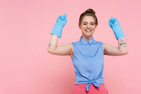 Aufgeregte und tätowierte Frau in Gummihandschuhen isoliert auf rosa — Stockfoto