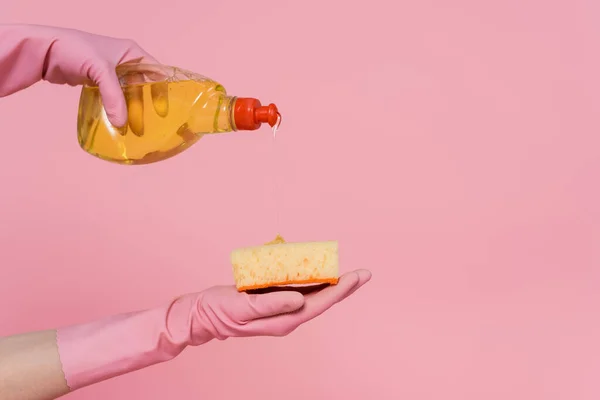 Abgeschnittene Ansicht einer Frau, die Waschmittel auf Schwamm gießt, isoliert auf rosa — Stockfoto