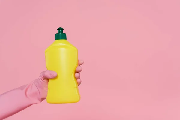 Vista cortada da mulher segurando garrafa amarela com detergente isolado em rosa — Fotografia de Stock