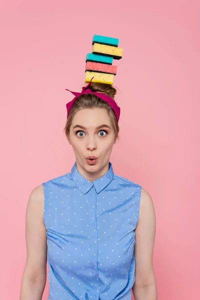 Überraschte junge Frau mit gestapelten Schwämmen auf dem Kopf — Stockfoto
