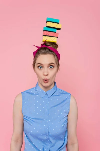 Surpris jeune femme avec des éponges empilées sur la tête isolé sur rose — Photo de stock