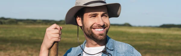 Jungbauer mit Krempenhut lächelt und schaut im Feld weg, Banner — Stockfoto