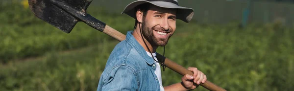 Agriculteur joyeux avec pelle regardant la caméra à l'extérieur, bannière — Photo de stock