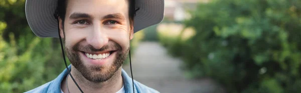 Retrato de jovem agricultor barbudo em chapéu brim sorrindo para a câmera, banner — Fotografia de Stock