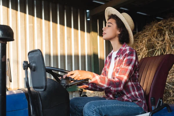 Side view of african american farmer driving tractor on farm — Stock Photo