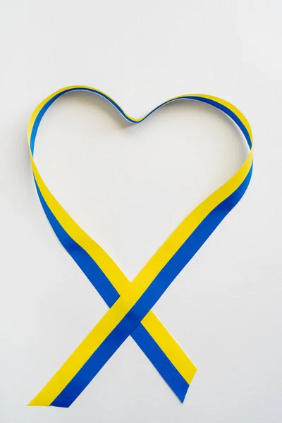 Вид сверху знака сердца с синей и желтой лентой на белом фоне — стоковое фото