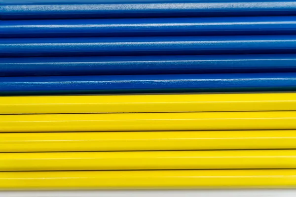 Vue du dessus des crayons de couleur jaune et bleue sur blanc — Photo de stock