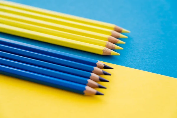 Vue rapprochée des crayons de couleur bleue et jaune flous sur le drapeau ukrainien — Photo de stock