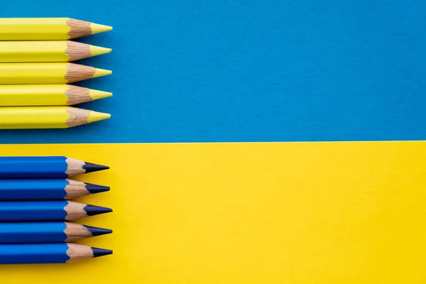 Vista superior de lápices de color azul y amarillo en la bandera de Ucrania - foto de stock