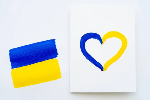 Top view of card with painted heart sign and ukrainian flag on white background — Stock Photo