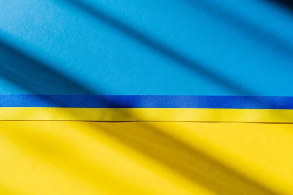 Vue du dessus du ruban bleu et jaune sur le drapeau ukrainien avec ombre — Photo de stock