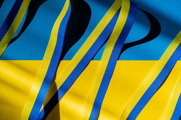 Top view of blue and yellow ribbon with shadow on ukrainian flag — Stock Photo