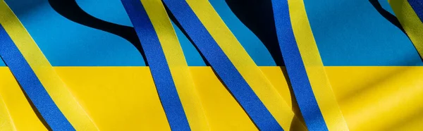 Top view of blue and yellow ribbon with shadow on ukrainian flag, banner — Stock Photo