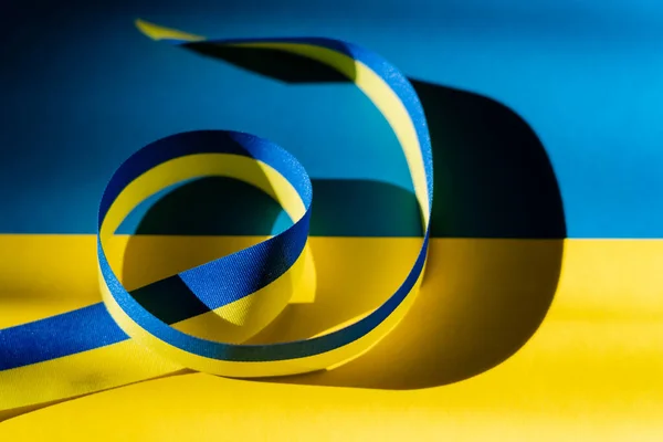 Close up view of blue and yellow ribbon with shadow on ukrainian flag — Stock Photo