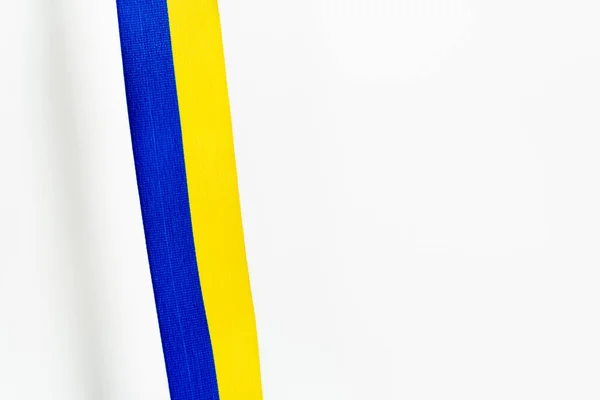 Top view of blue and yellow ribbon with shadow on white background — Stock Photo