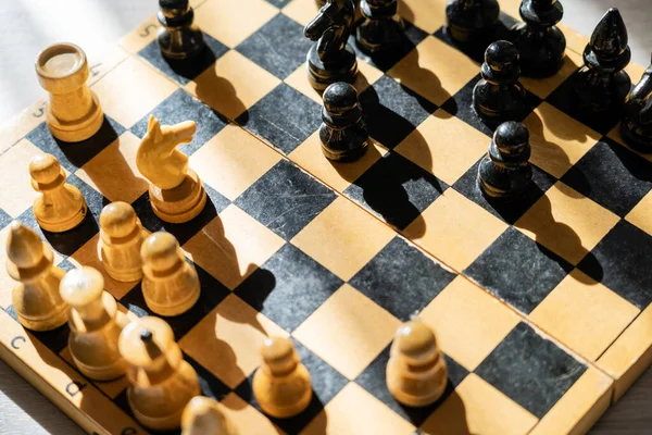 Vista superior do xadrez no tabuleiro de xadrez de madeira com sombra na superfície de madeira — Fotografia de Stock