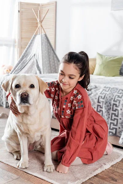 Joyeux preteen fille étreignant labrador jaune regardant caméra — Photo de stock