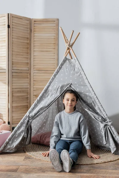 Pleine longueur vue de fille heureuse assis sur le sol dans wigwam — Photo de stock