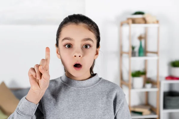 Erstauntes Mädchen blickt in die Kamera und zeigt Ideengeste — Stockfoto