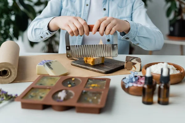 Vista ritagliata di artigiana taglio sapone vicino stampo in silicone sfocato e carta artigianale — Foto stock