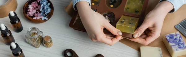 Top view of craftswoman taking handmade soap from silicone mold at home, banner — Stock Photo