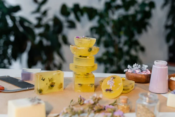 Barras de jabón orgánicas hechas a mano cerca de flores secas borrosas en la mesa - foto de stock