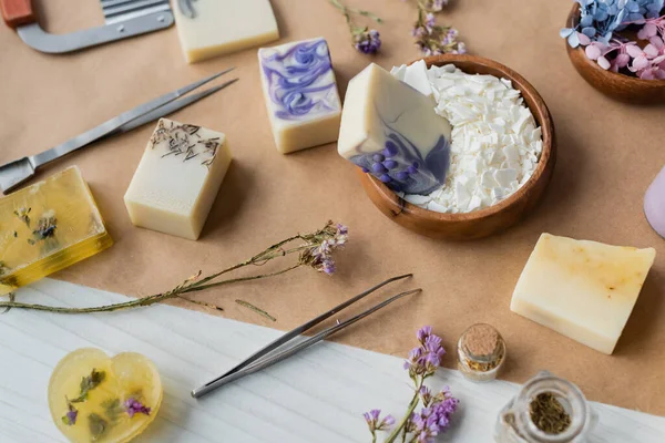 Vue grand angle des barres de savon faites à la main près des fleurs sèches et des fournitures sur du papier artisanal — Photo de stock