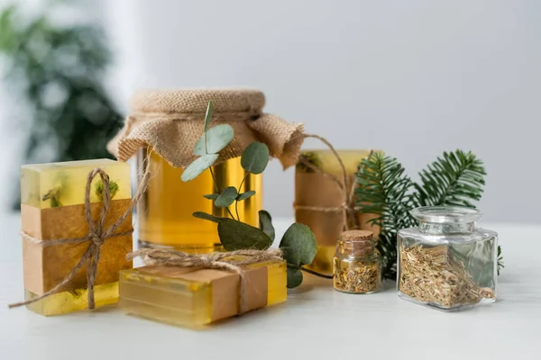 Handmade soap bars near honey, eucalyptus and herbs on table — Stock Photo