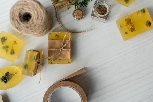 Top view of craft soap bars with flowers and twine on table — Stock Photo