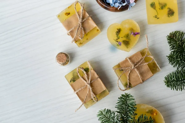 Top view of handmade soap bars near flowers and pine branches on table — Stock Photo