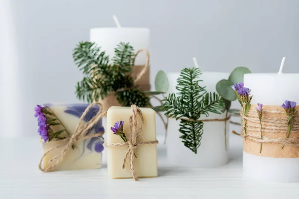 Barres de savon artisanales près des bougies avec branches d'épinette sur fond gris — Photo de stock