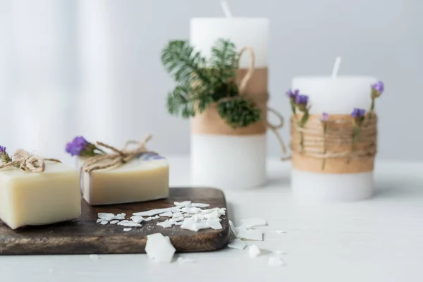 Savon artisanal sur planche à découper près des bougies floues sur la table — Photo de stock