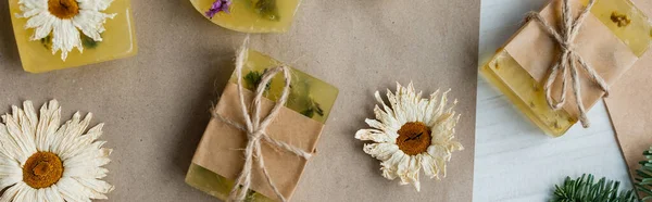 Top view of dry romomiles near handmade soap on craft paper, banner — стоковое фото