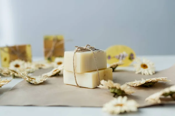 Handmade soap near blurred chamomiles on craft paper — Stock Photo