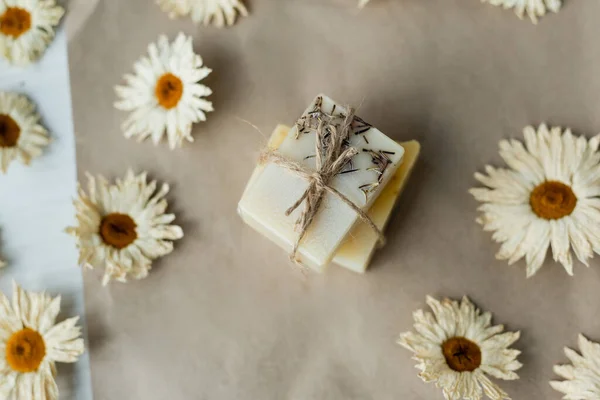 Ansicht von handgemachter Seife mit Bindfaden in der Nähe von Kamillen auf Bastelpapier — Stockfoto