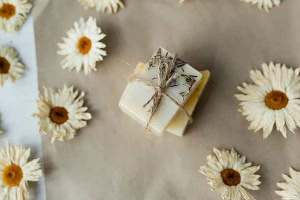 Top view of handmade soap with twine near chamomiles on craft paper — Stock Photo