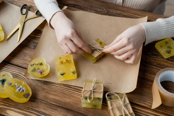 Handwerkerin verpackt handgemachte Seife auf Bastelpapier auf dem Tisch — Stockfoto