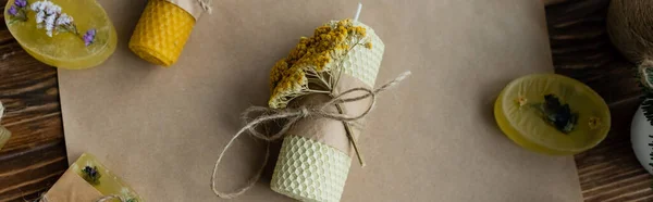 Vista dall'alto di candele artigianali e sapone con fiori secchi su carta su superficie di legno, banner — Foto stock