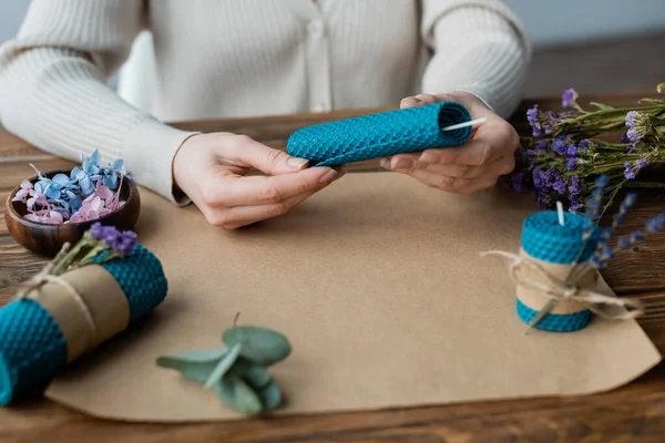 Cropped view of blurred craftswoman making candle with wick near flowers on table — Stock Photo