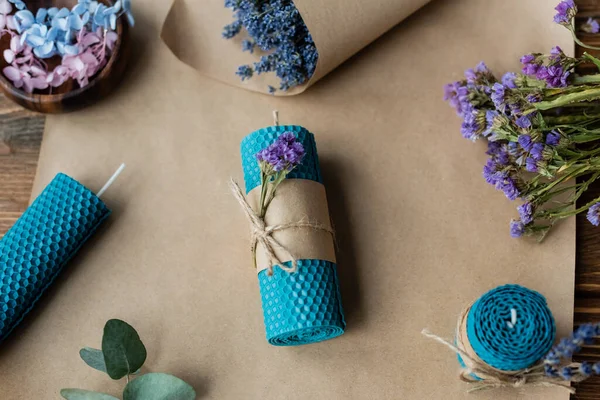 Vista dall'alto della candela fatta a mano vicino alla lavanda su carta artigianale su superficie di legno — Foto stock