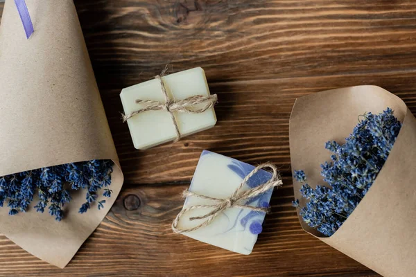 Vue de dessus du savon fait à la main près des bouquets de lavande sur la surface en bois — Photo de stock