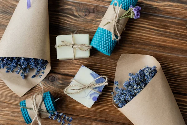 Top view of lavender flowers near handmade soap and candles on wooden surface — Stock Photo