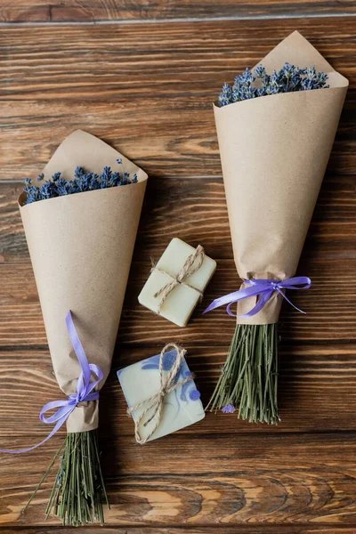 Vue de dessus des bouquets de lavande près des savonnettes artisanales sur la surface en bois — Photo de stock