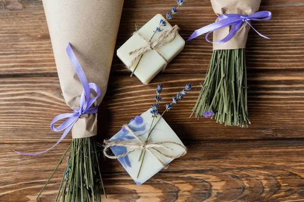 Vue du dessus des barres de savon faites à la main près des bouquets sur la surface en bois — Photo de stock